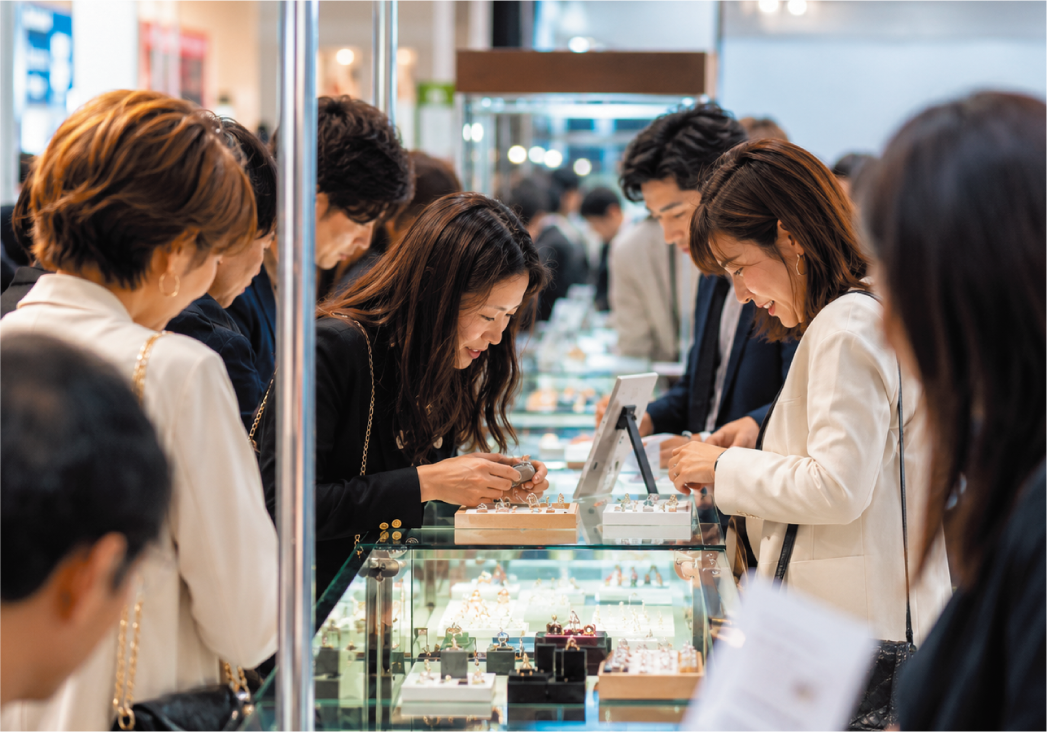 ジュエリーのショーケースを囲み、商品を確認しながら商談する来場者と出展社